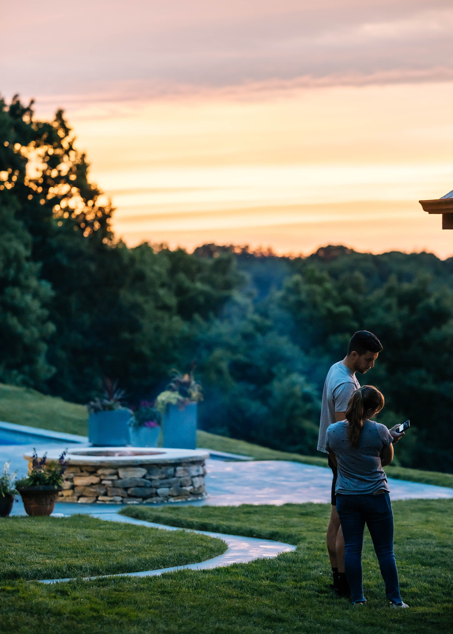 Two people standing in the backyard of their custom home looking at a phone.