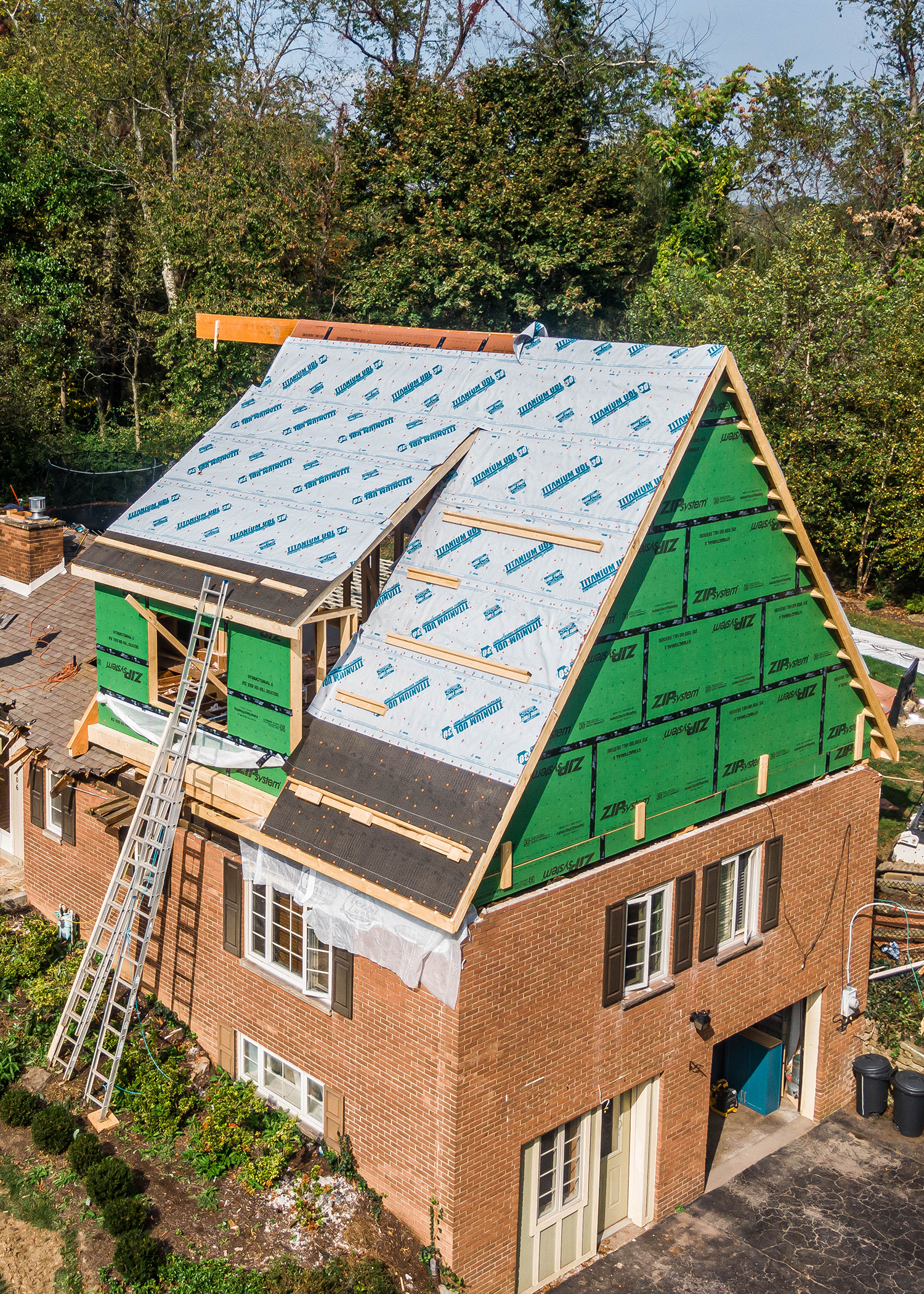 A framed custom home with roof work being completed.