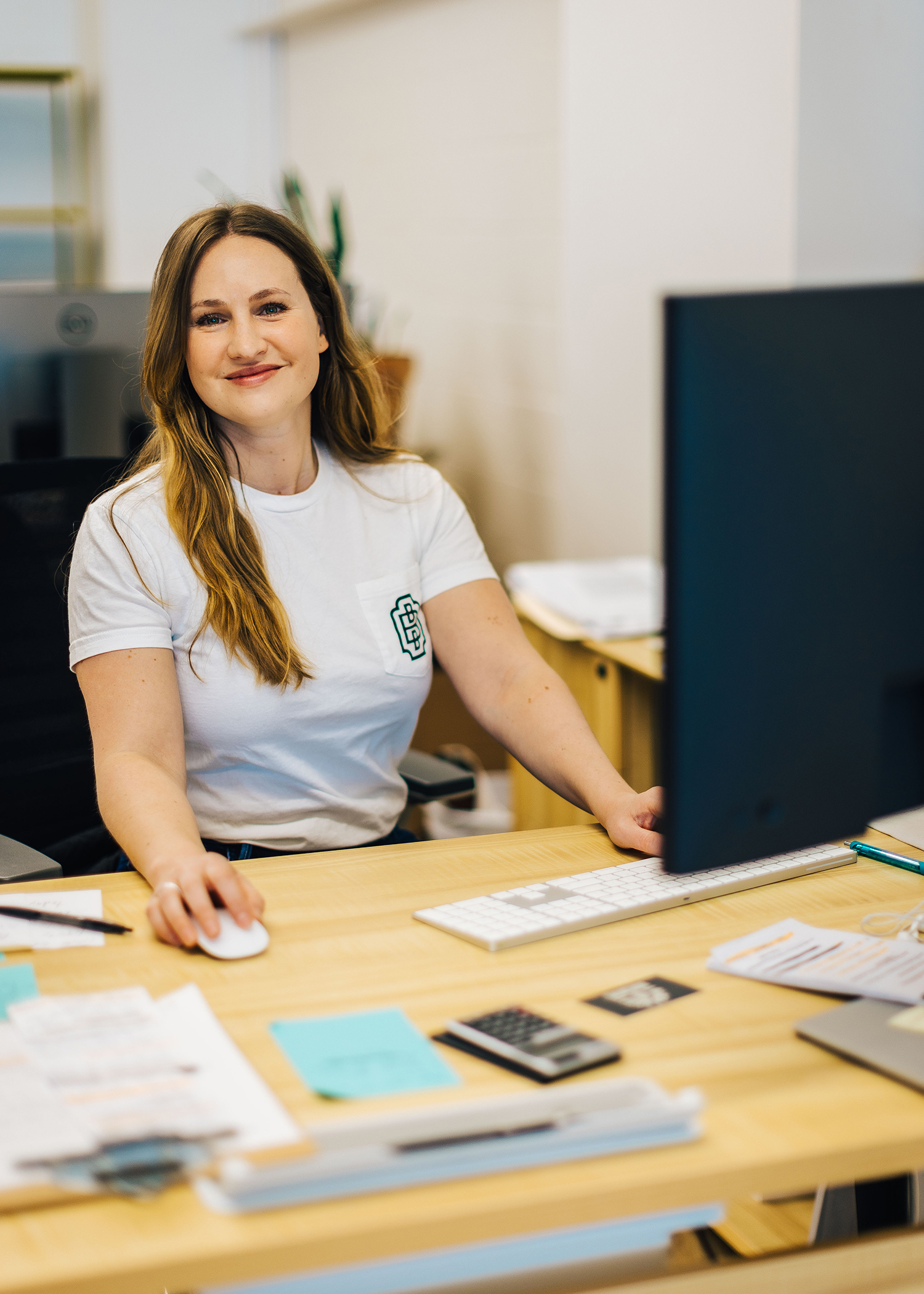 A Black Boot Builder employee smiling at the camera while at her desk.