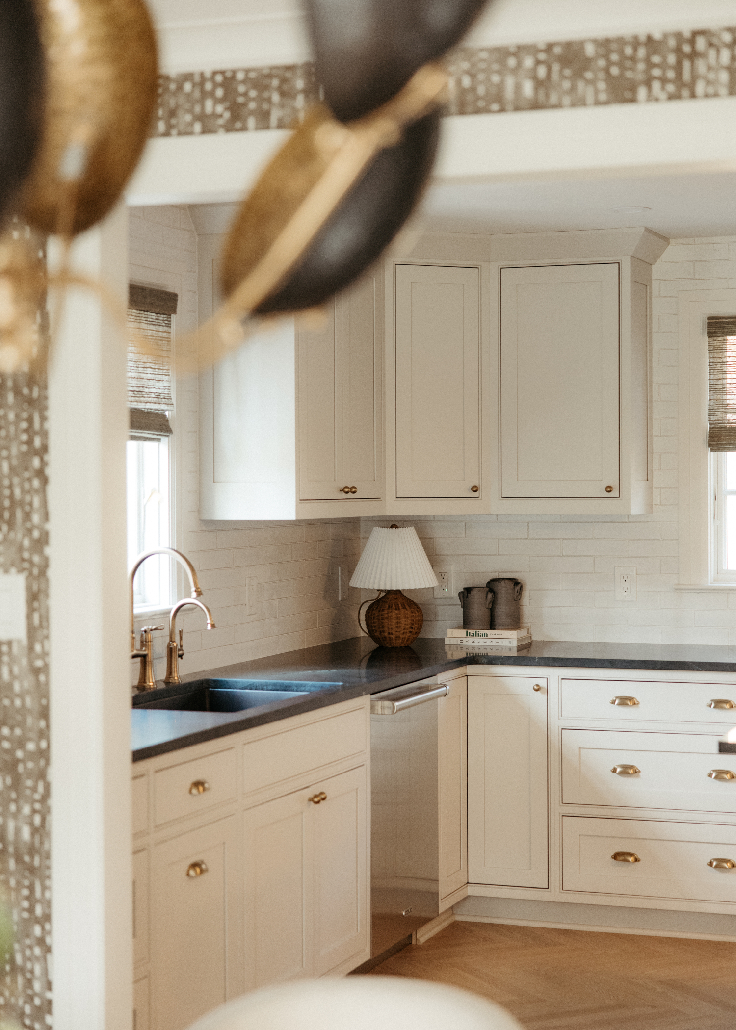 A renovated kitchen with white cabinets and a black countertop with a lamp.