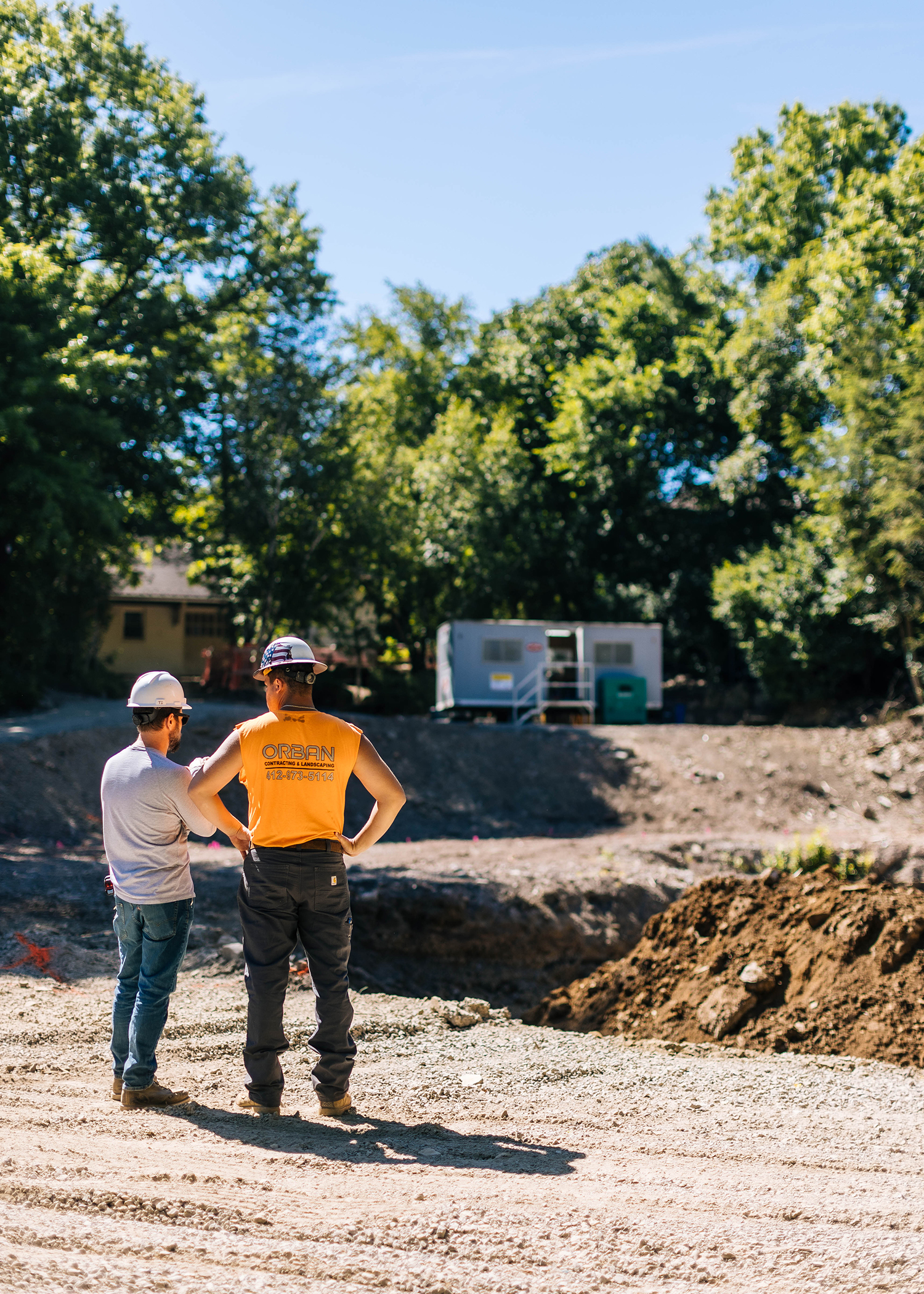 Workers standing outside overseeing a site preparation area.