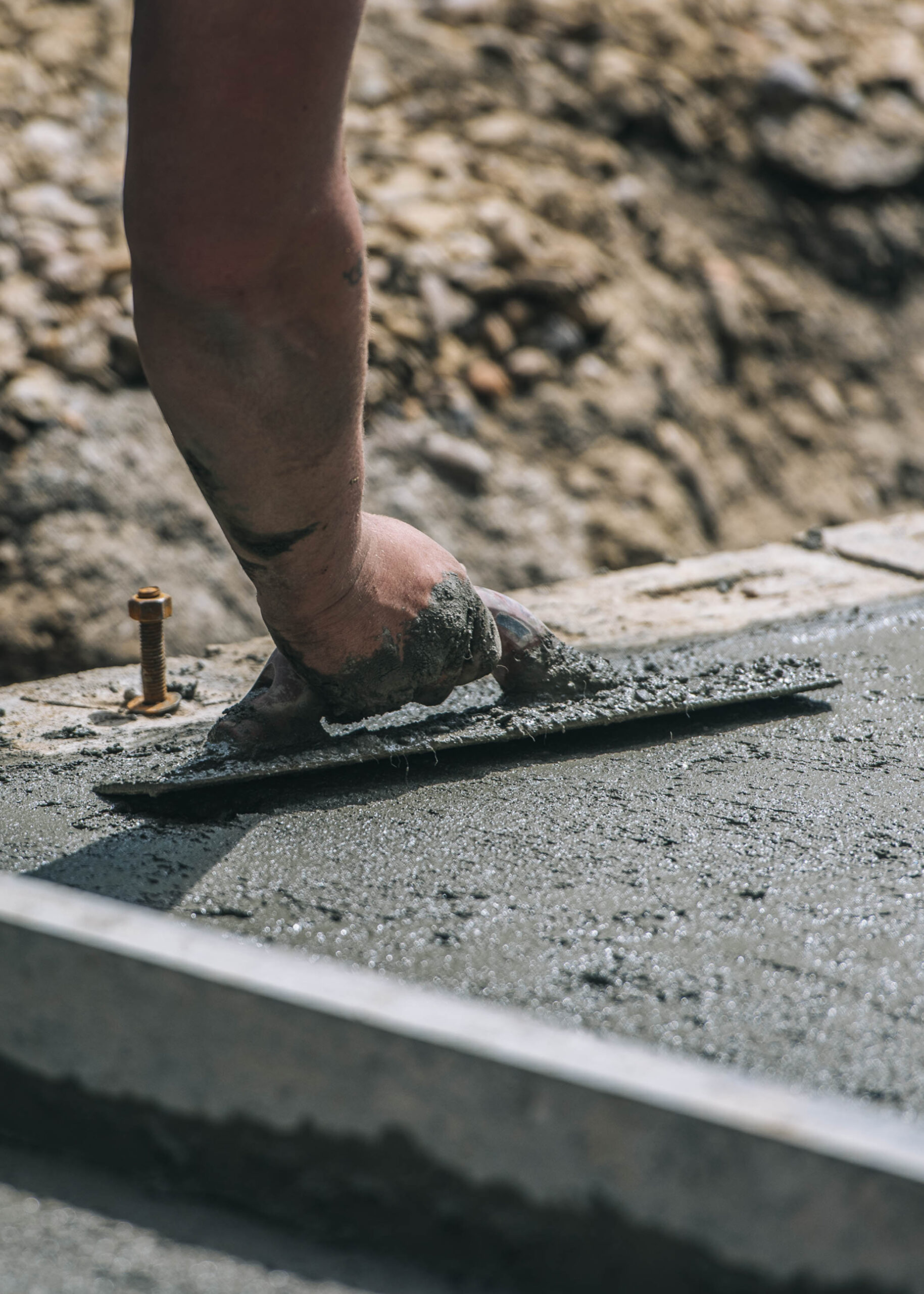 Construction worker smoothing cement for site preparation.